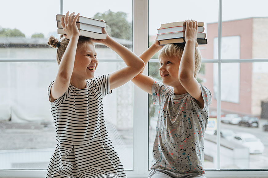 Photo of siblings with books on their heads
