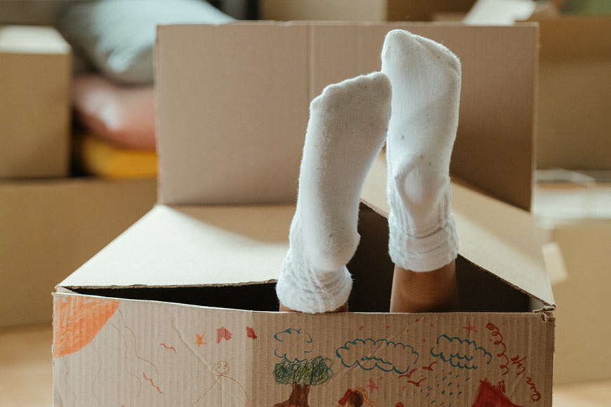 Photo Of A Child's Socked Feet Sticking Out Of A Cardboard Box