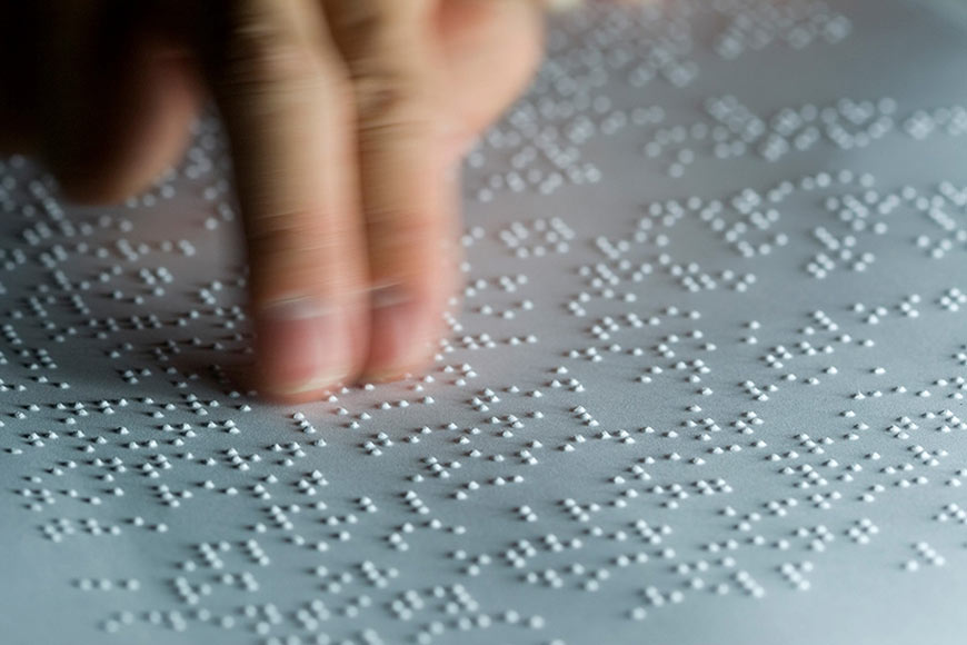 Photo of a hand running over braille