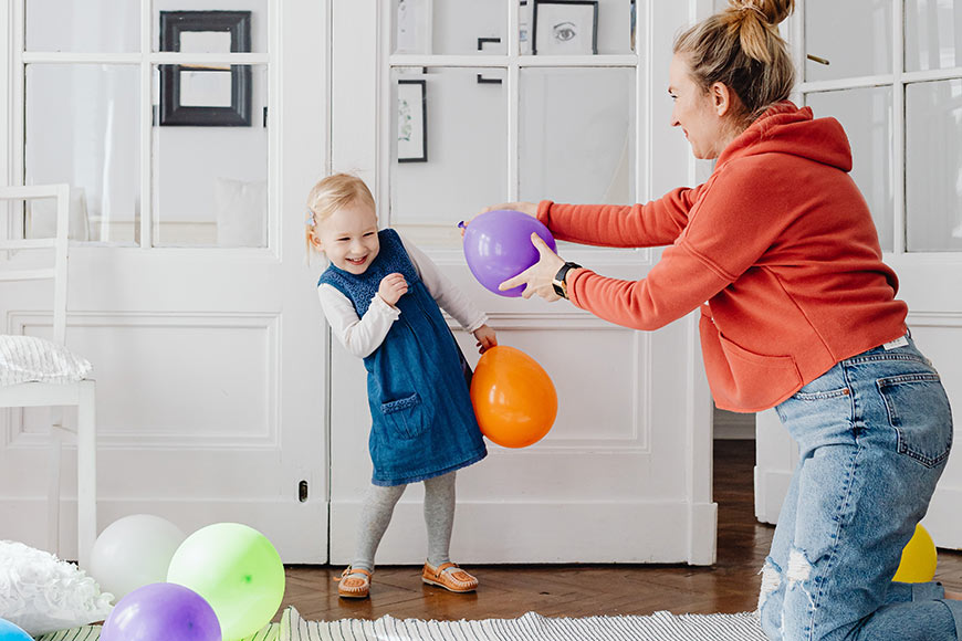 Photo of a little girl and her mother playing with balloons