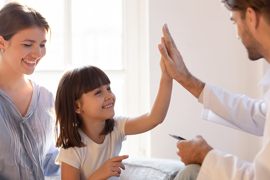 Photo of a little girl high-fiving a therapist