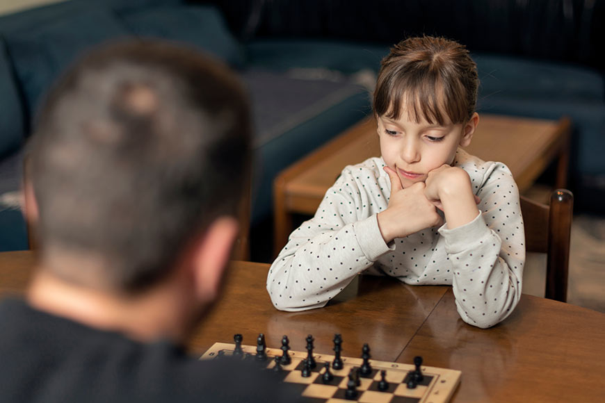 Photo of a little girl playing chess