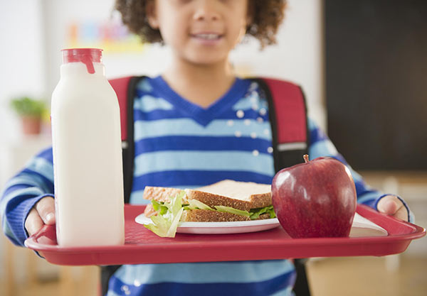 Photo of a little boy carrying a lunch tray