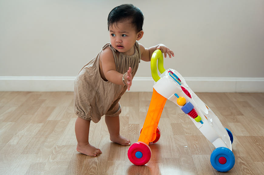 Photo of a baby pushing a toy walker