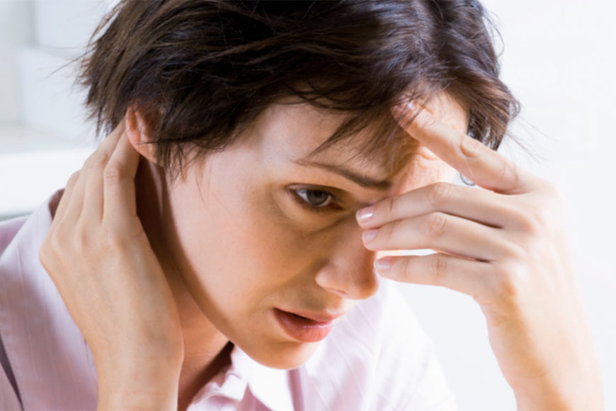 Photo of a woman holding her forehead and neck looking stressed out