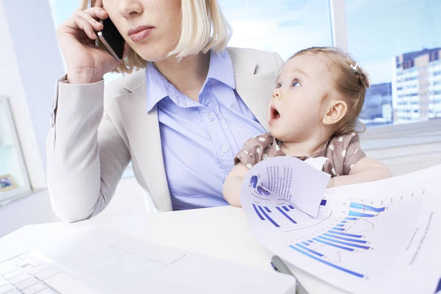 Photo of a professional woman talking on the phone while holding a baby