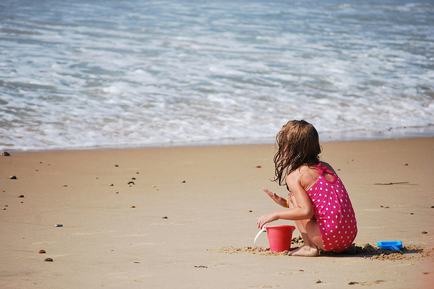 Photo of a little girl playing on the beach