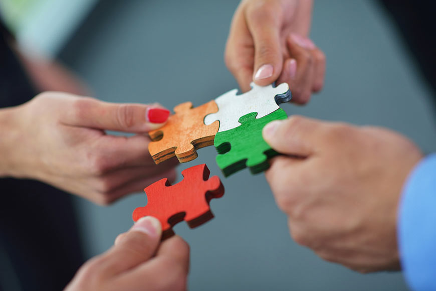 Photo of people holding puzzle pieces together