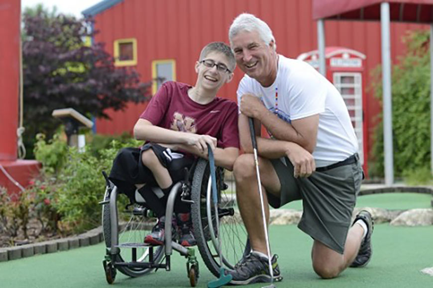 Photo of Mark Schumacher playing golf with disabled child
