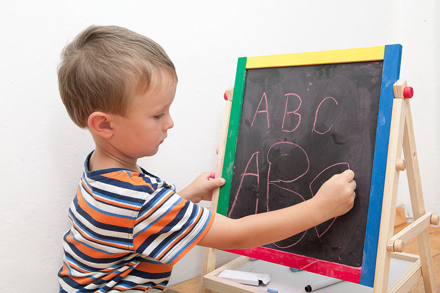 Photo of a little boy writing on a chalkboard